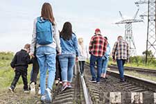 Immigrants waling on rail road.