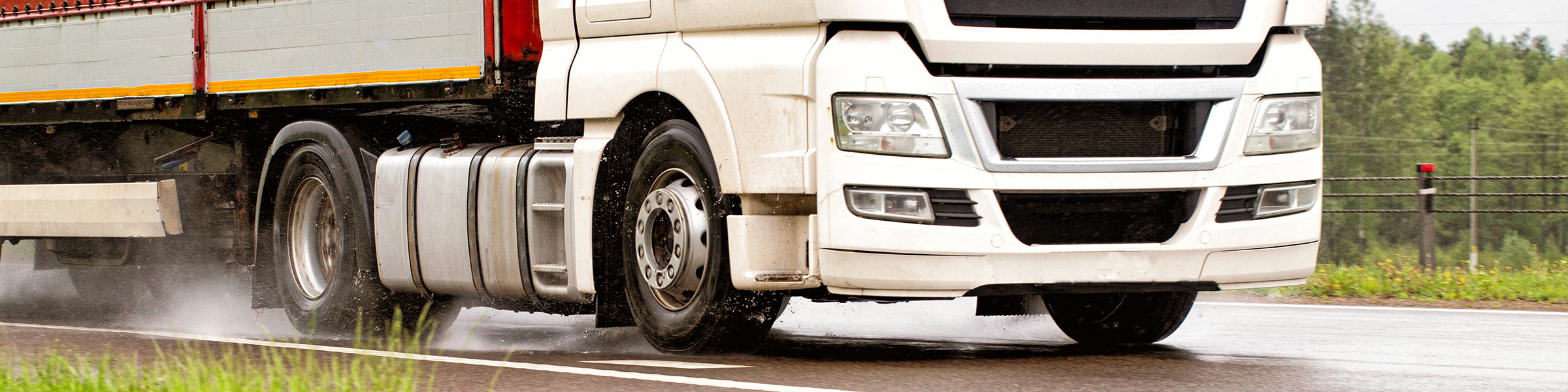 Semi truck cruising on wet road.