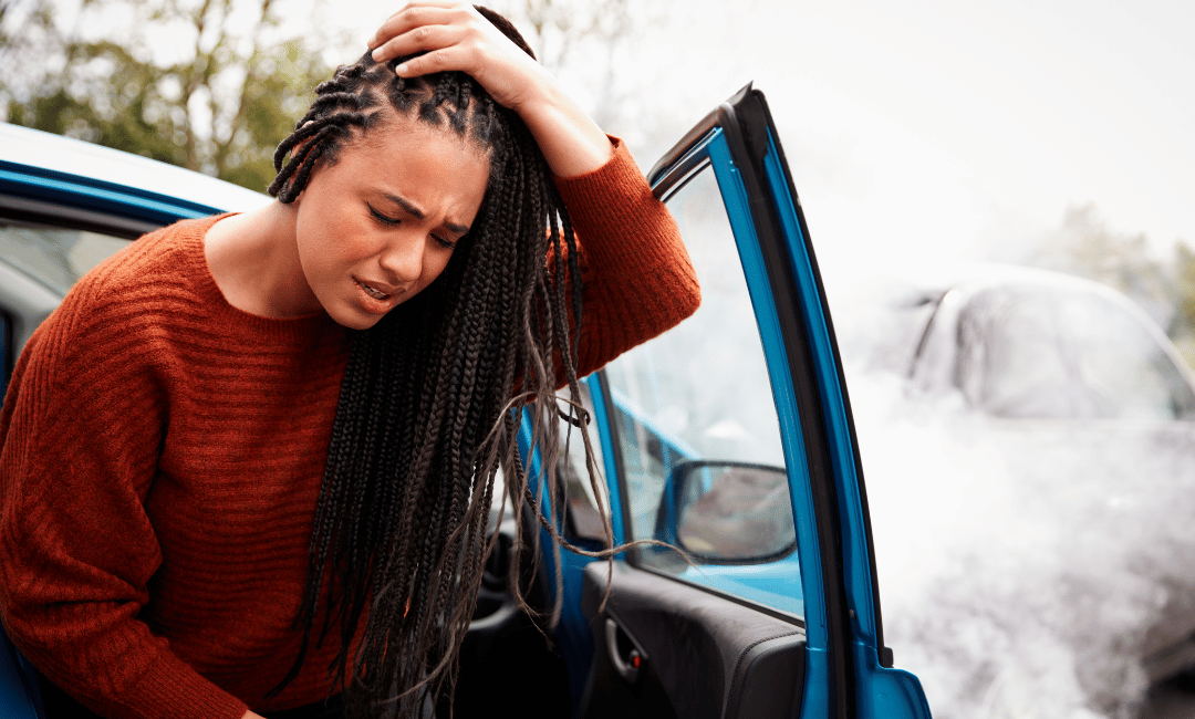 auto accident victim getting out of car holding top of head