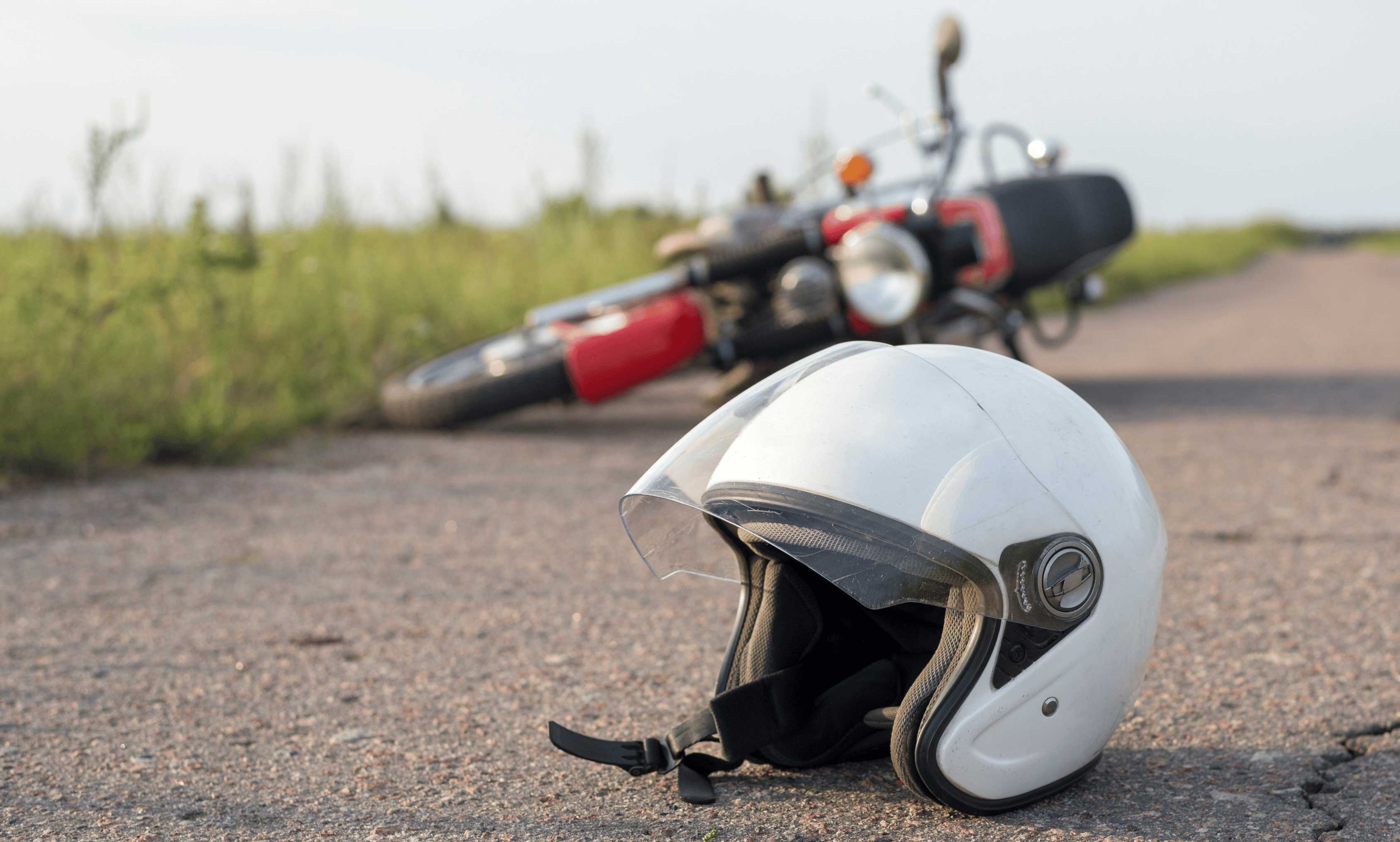red motorcycle layin on side with white helmet