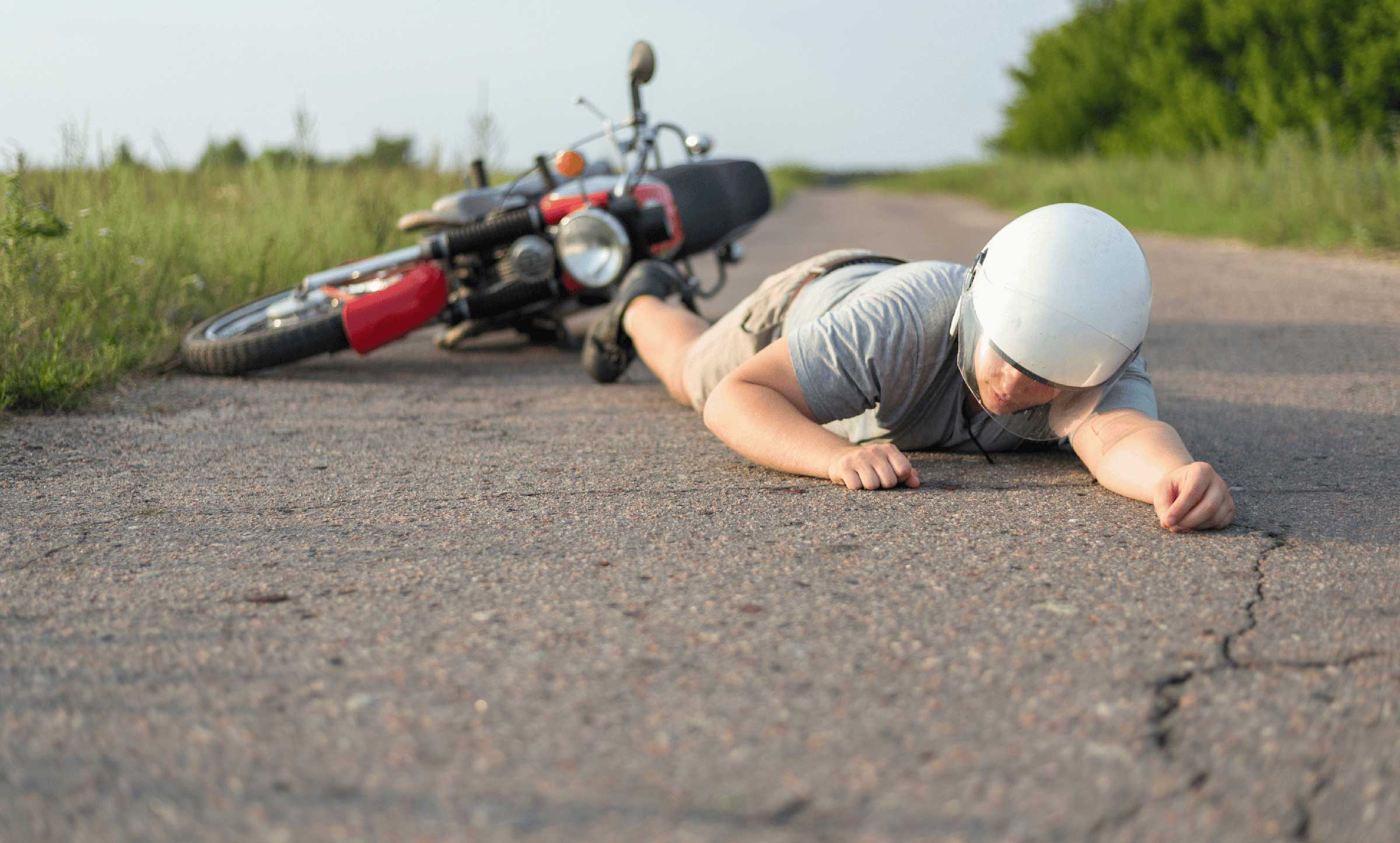 red motorcycle laying on side with injured rider