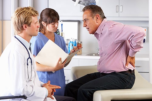Photo of male accident victim with back pain visiting doctor