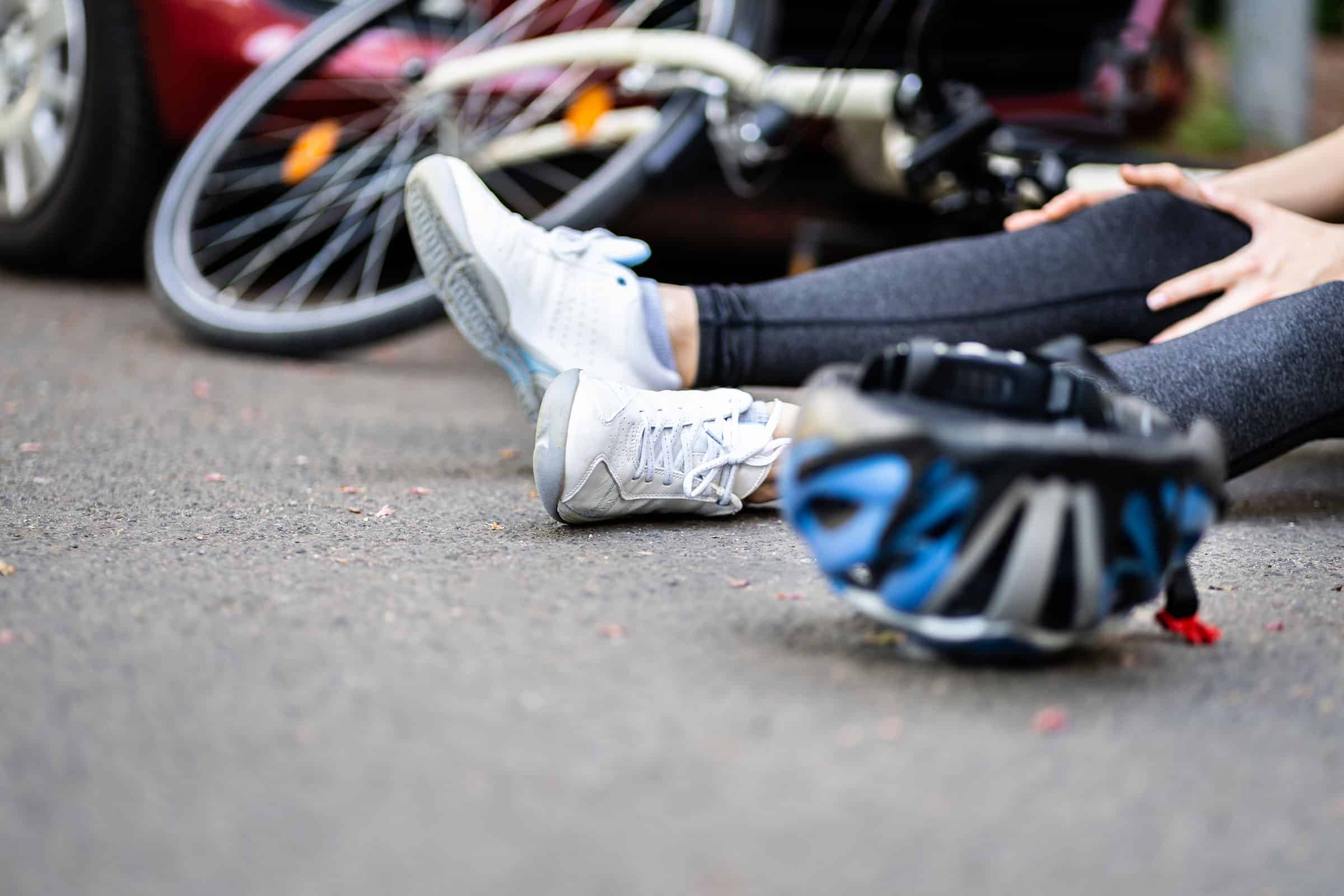 Bicycle rider hit by car.  Rider on ground holding leg.