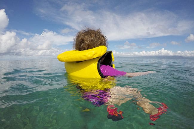 little girl in yellow life jacket floating alone in ocean