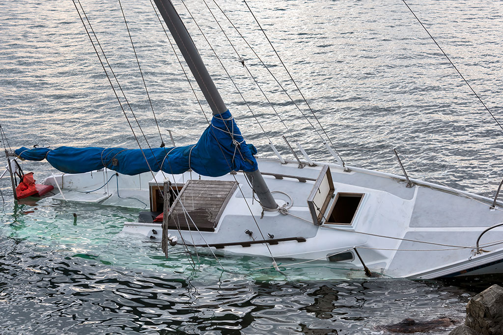 white sail boat sinking due to boat accident