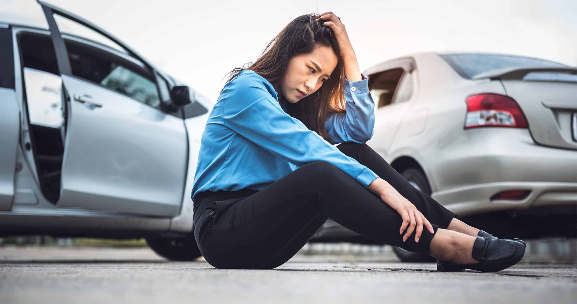 Business woman sitting on ground after car accident waiting for EMS