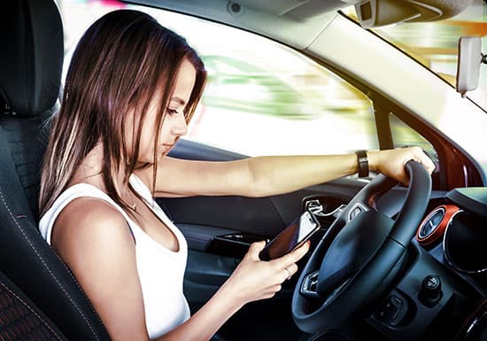 young womanlooking at mobile phone while driving