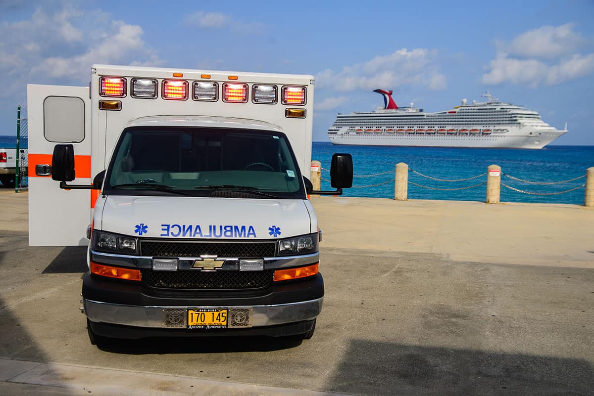 image - ambulance waiting at cruise ship port to receive passenger from cruise ship approaching in ocean