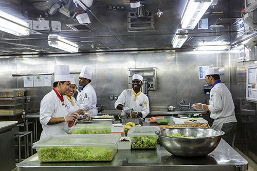 image - 6 cruise ship crew members in white uniforms and chef hats in kitchen preparing food