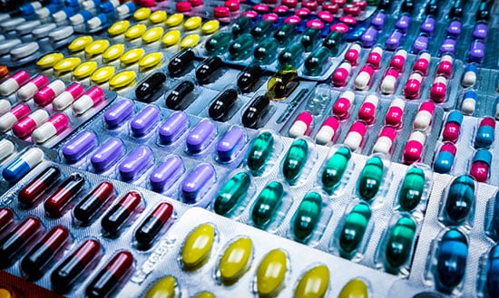 colorful tablets and capsules pills in blister packagine arranged in pattern
