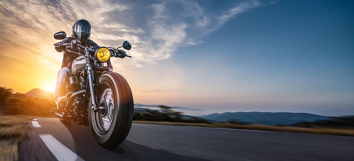 Motorcyclists riding on open road at sunset