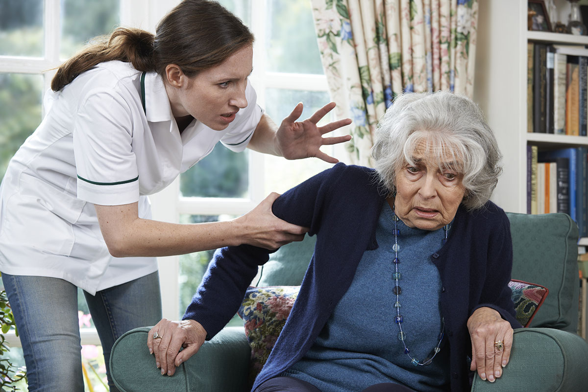 Care giver yelling at elderly woman in nursing home