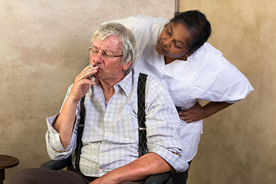 Elderly man in wheel chair smoking in nursing home