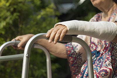 elderly woman with walker and fractured arm in cast