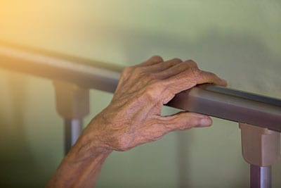 Hand of old woman on bed rail