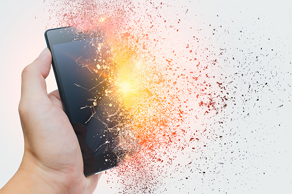 Show thumbnail preview A hand holds a smartphone that appears to be shattering and disintegrating into particles, with bright light and fragments dispersing to the right, symbolizing destruction or digital breakdown.