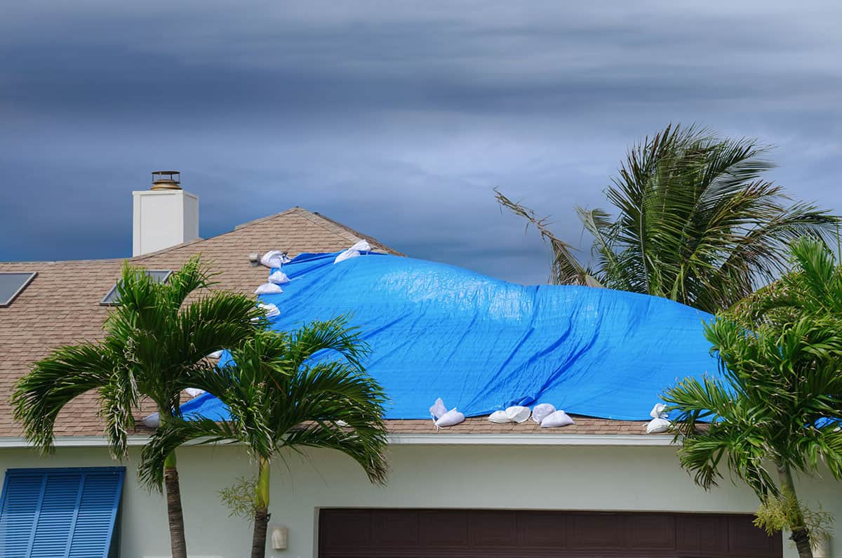 Roof with blue tarp damaged by hurricane