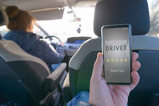 rideshare passenger in back seat of car using smartphone app to rate a driver