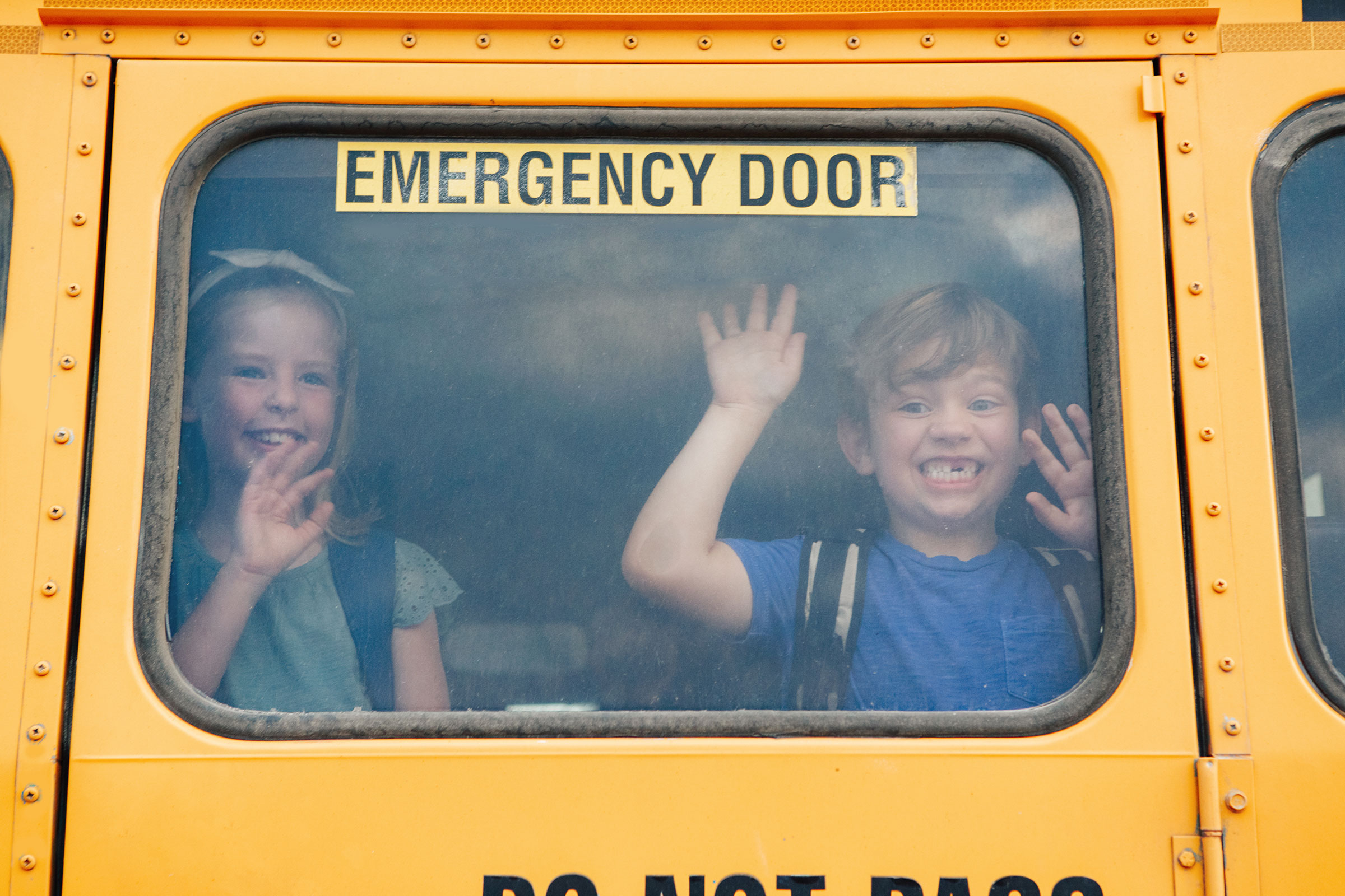 boy and girl looking out back door of school bus