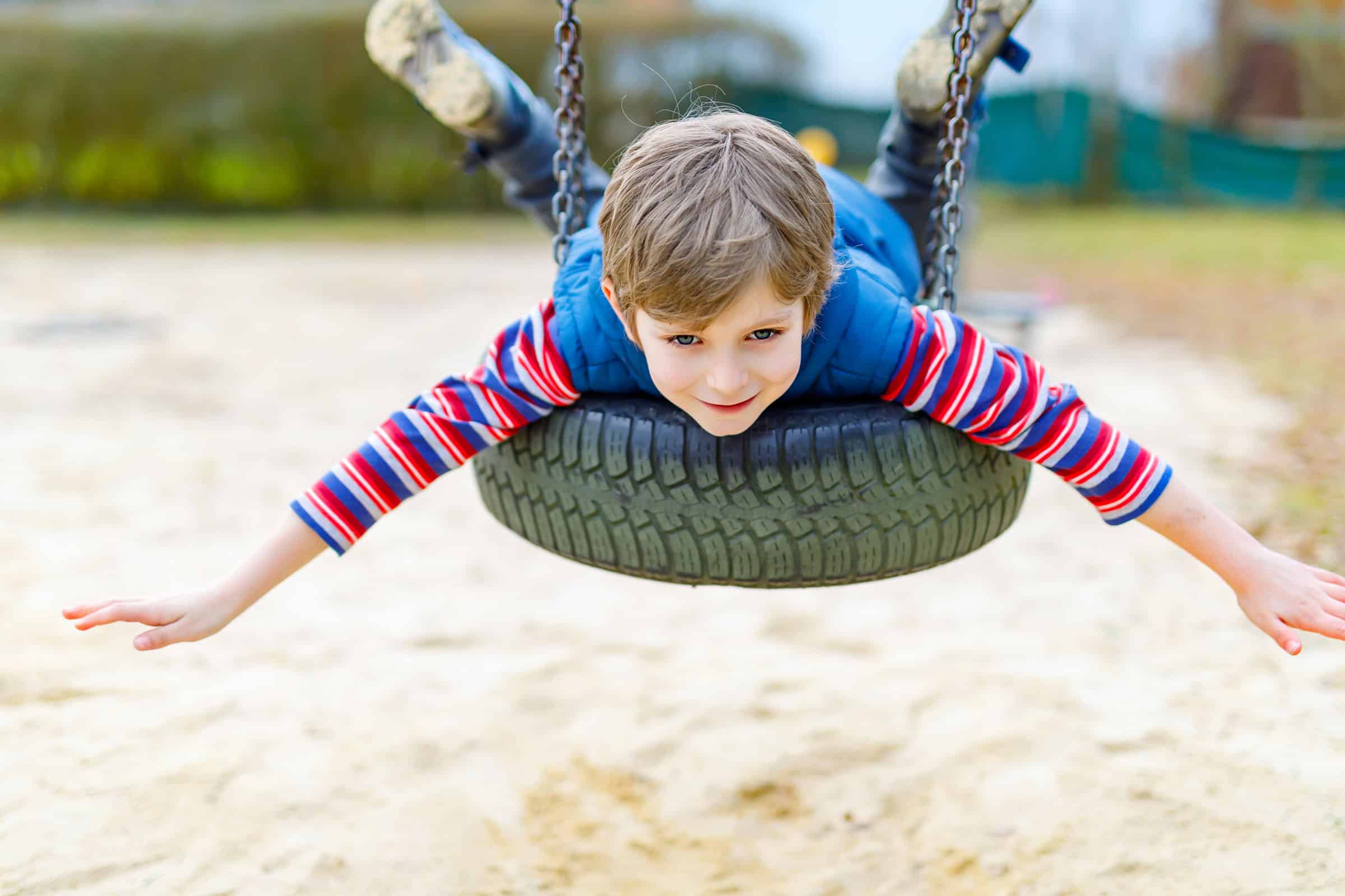 child-on-belly-on-tire-swing-on-playground