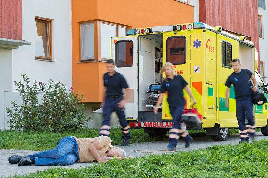 slip and fall accident photo of paramedics with yellow ambulance and fallen senior citizen laying on sidewalk