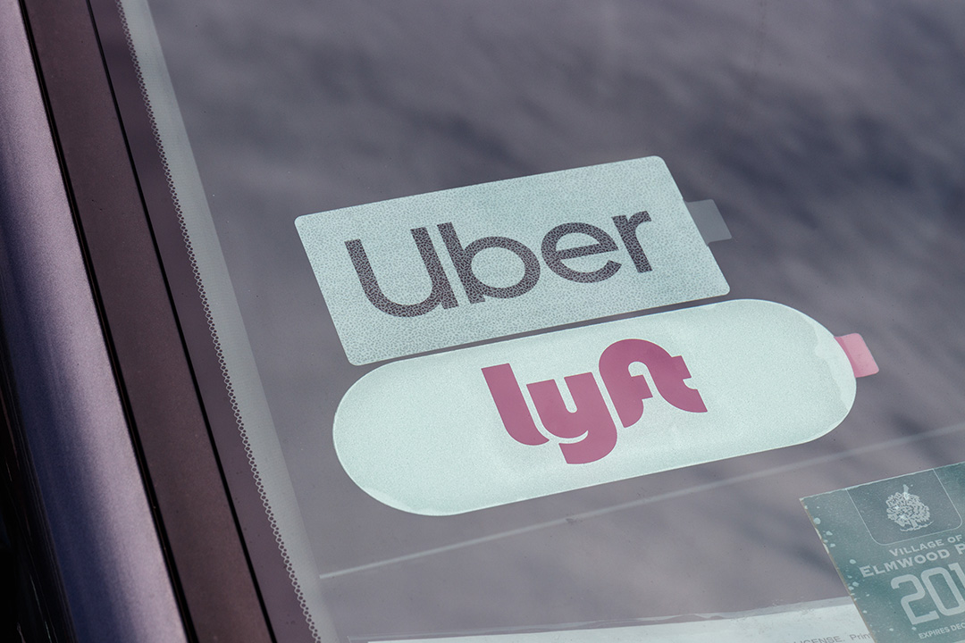 Show thumbnail preview A car windshield displaying Uber and Lyft stickers side by side, indicating the vehicle is used for ride-sharing services. A permit sticker is also visible in the lower right corner.