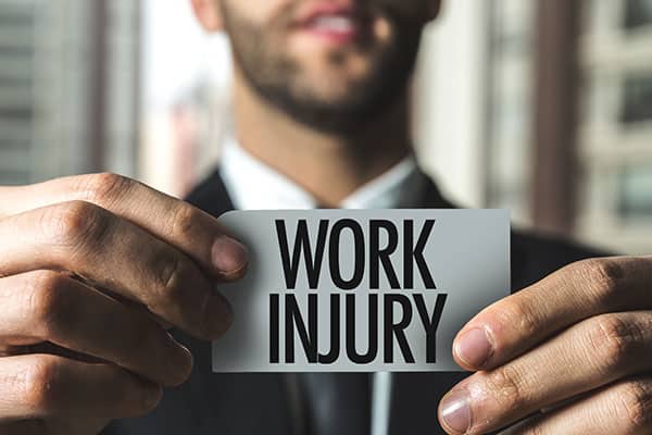 man holding small sign with both hands that reads work injury